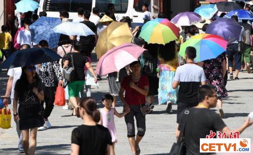 7月12日，厦门一景点游客们纷纷打起伞遮挡烈日。张斌 摄